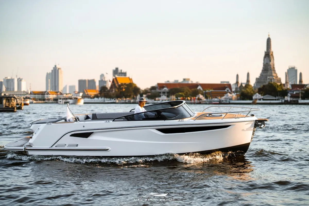 Alfastreet Marine 23 Cabin Evo Electric: Ein Boot, das auf einem Fluss mit einer Skyline fährt