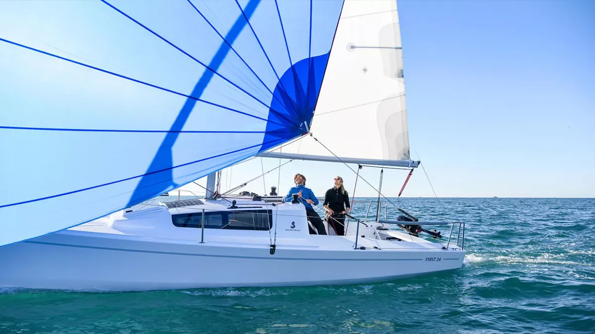 Beneteau First 24: Segelboot mit blauem Spinnaker auf dem Meer