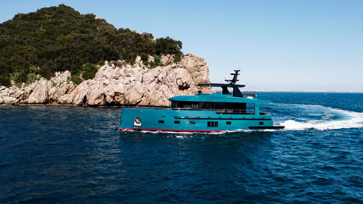 Bering Yachts B78: A turquoise yacht sails along the coast