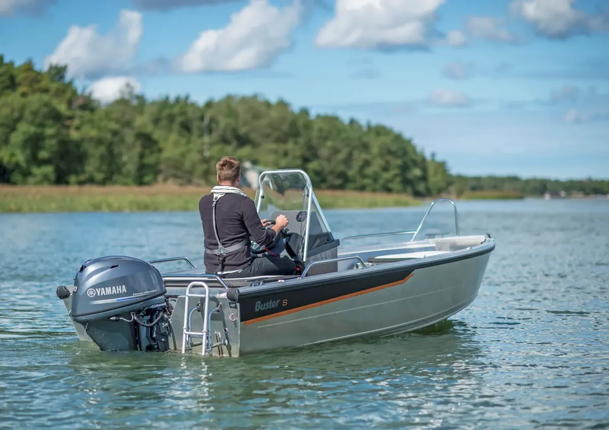 Buster Scc: A man steering a boat on a lake