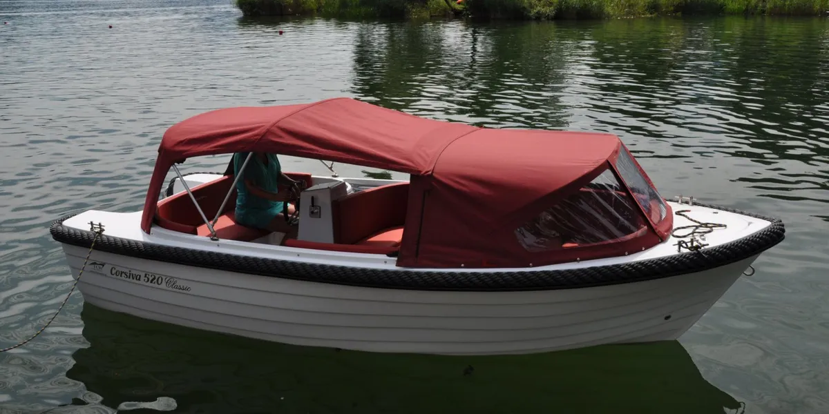Corsiva 520 Classic: White boat with a red canopy on the water