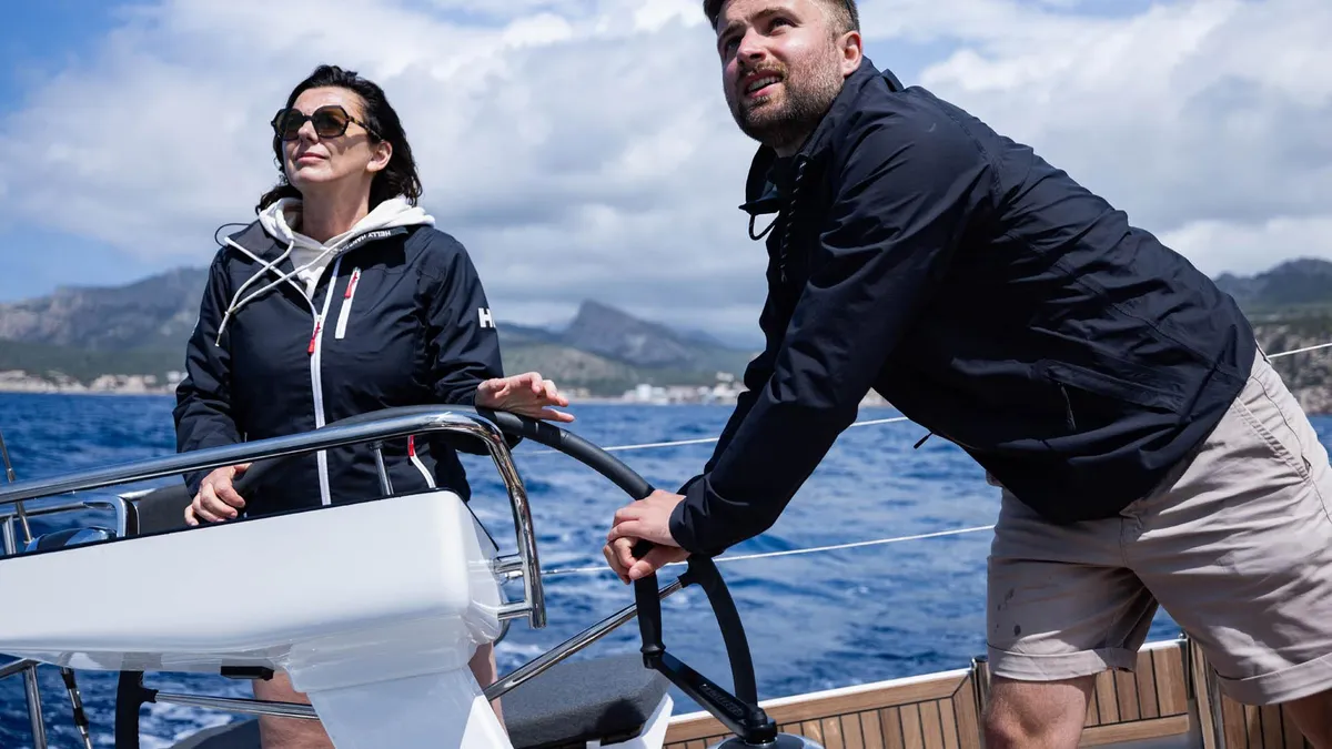 Jeanneau Sun Odyssey 455: Couple steering a sailing boat at sea