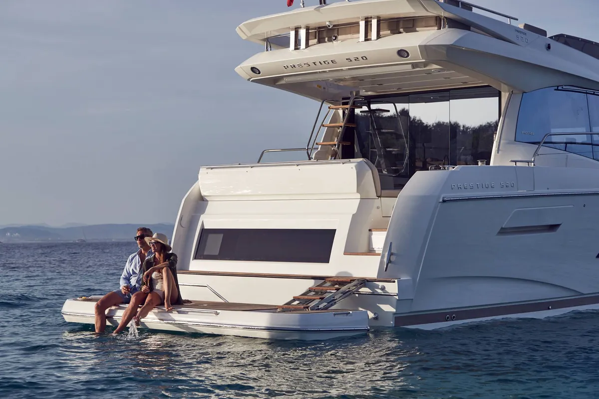 Prestige Yachts 520: Couple sitting on a boat’s swimming platform