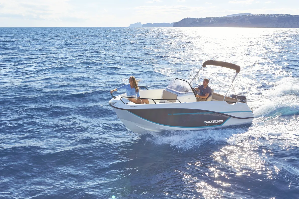 Quicksilver 475 aXess: Ein Boot fährt auf dem Meer, im Hintergrund ist die Küste zu sehen