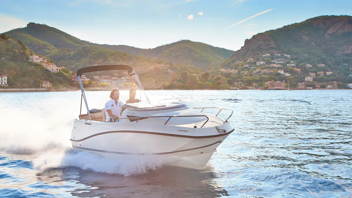 Quicksilver 505 Cabin: Un bateau naviguant au large d'une côte bordée de montagnes