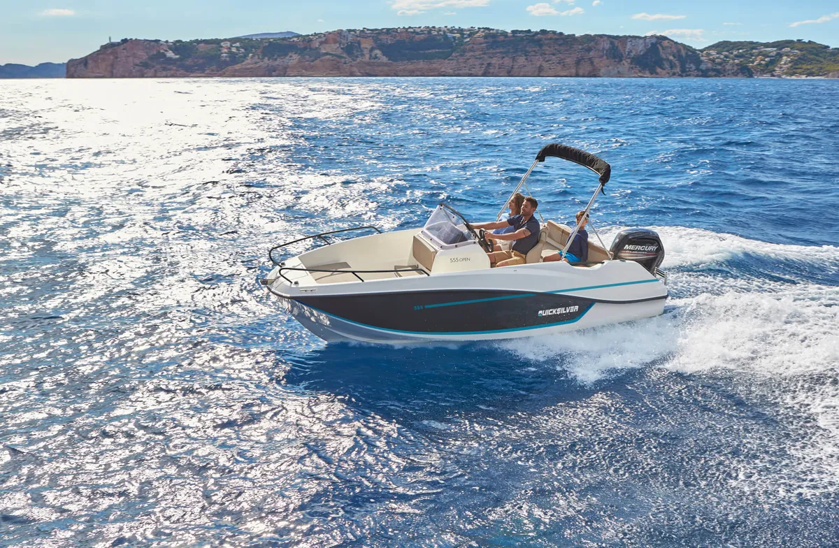 Quicksilver 555 Open: Boat cruising at sea with the coast in the background