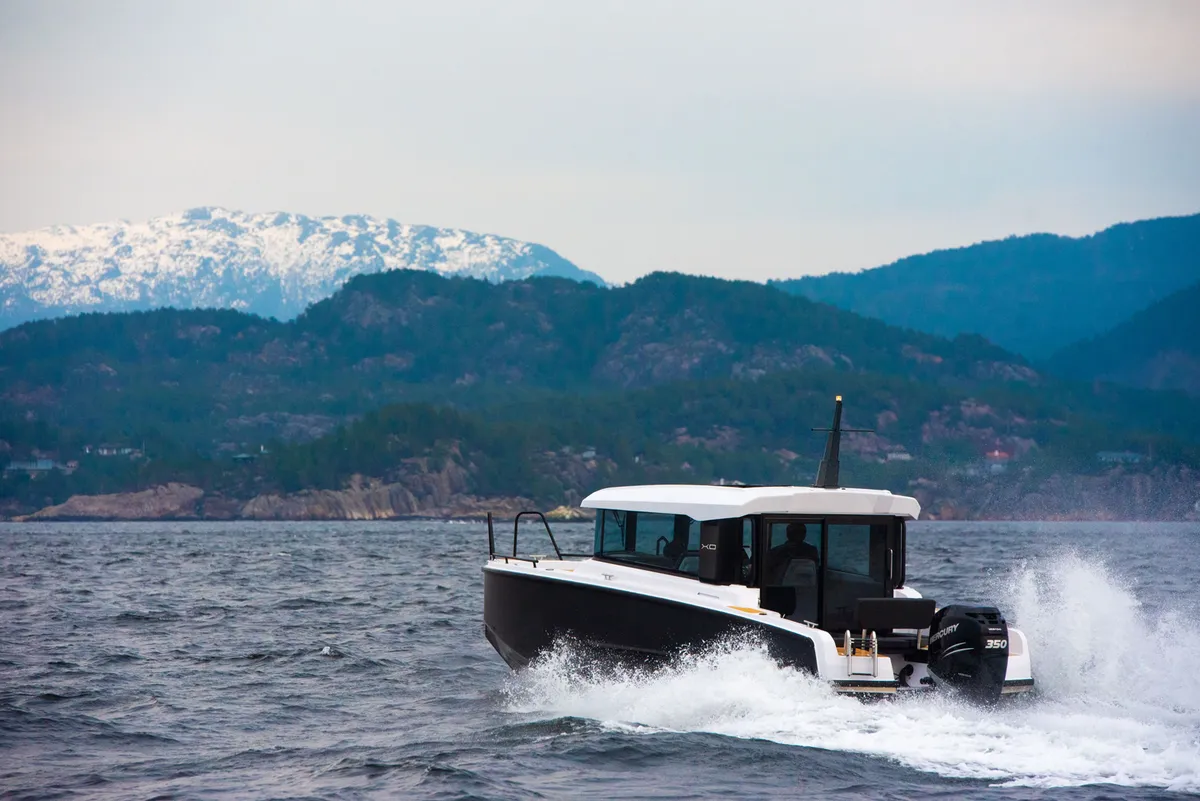 XO Boats EXPLR 9: Boat cruising at sea with mountains in the background